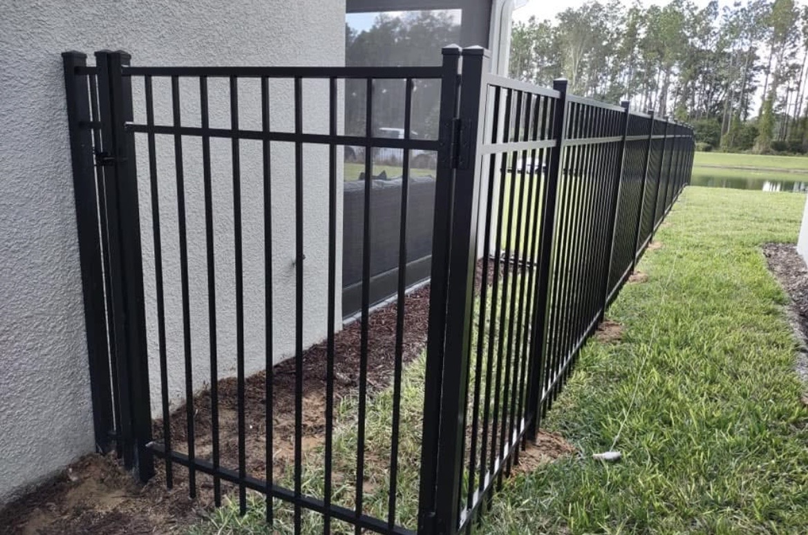 Black aluminum fence and gate beside a pool enclosure