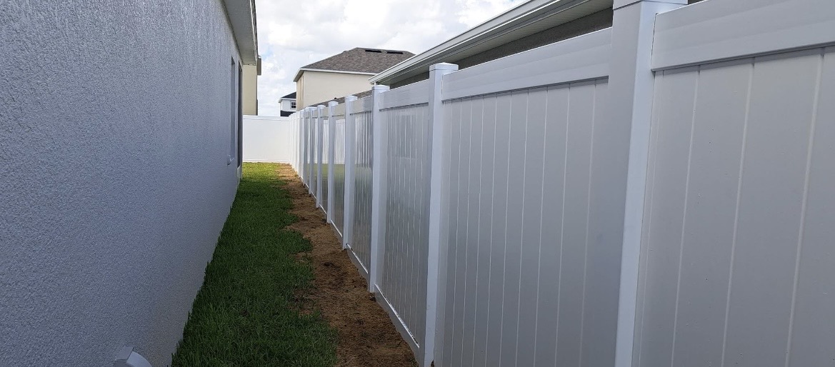 White vinyl privacy fence installed along a home