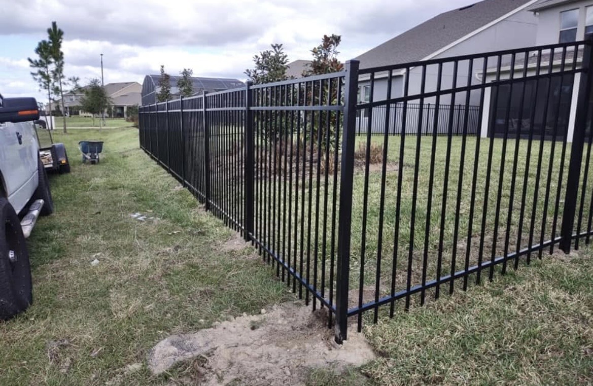 Long run of black aluminum fencing across a backyard